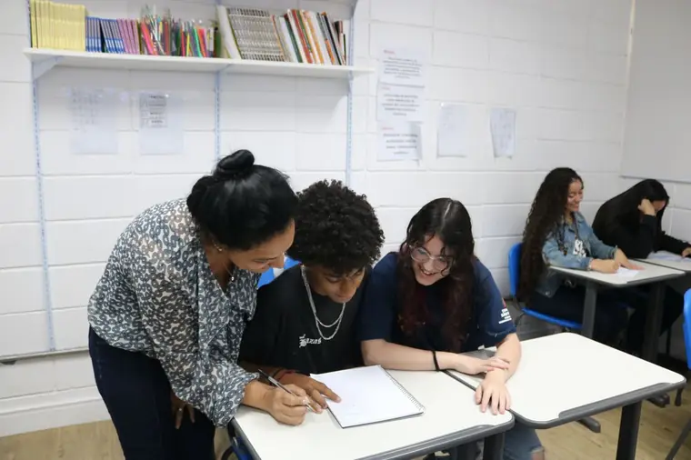 Mentora orientando jovens durante uma atividade em sala